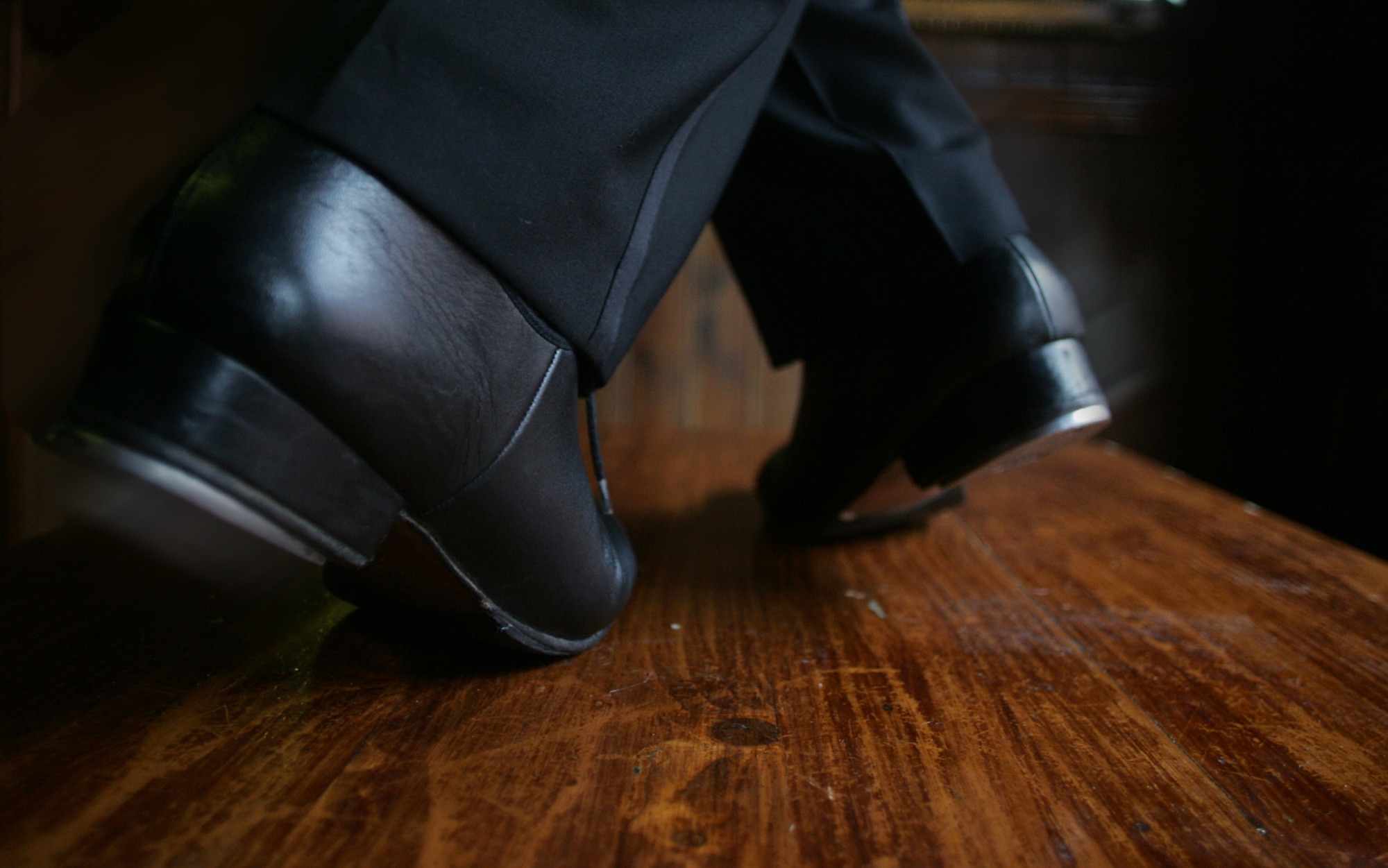 Close-up of dancing shoes mid-step on a polished wooden table